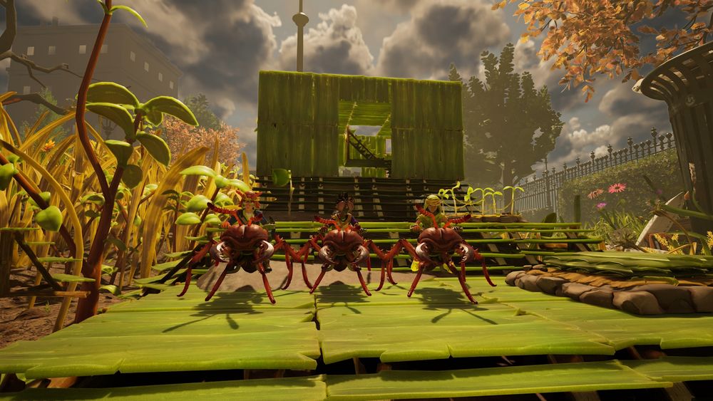 uma imagem do jogo grounded 2, com 3 pessoas (em miniatura) montadas em cima de 3 formigas posando para uma foto, com uma casa feita de grama no fundo e um jardim enorme ao redor