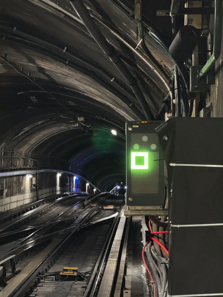 Photo of the new STM signal box, with it being lit up in bright green.

The old signal box is covered in a dark tarp and zip ties
