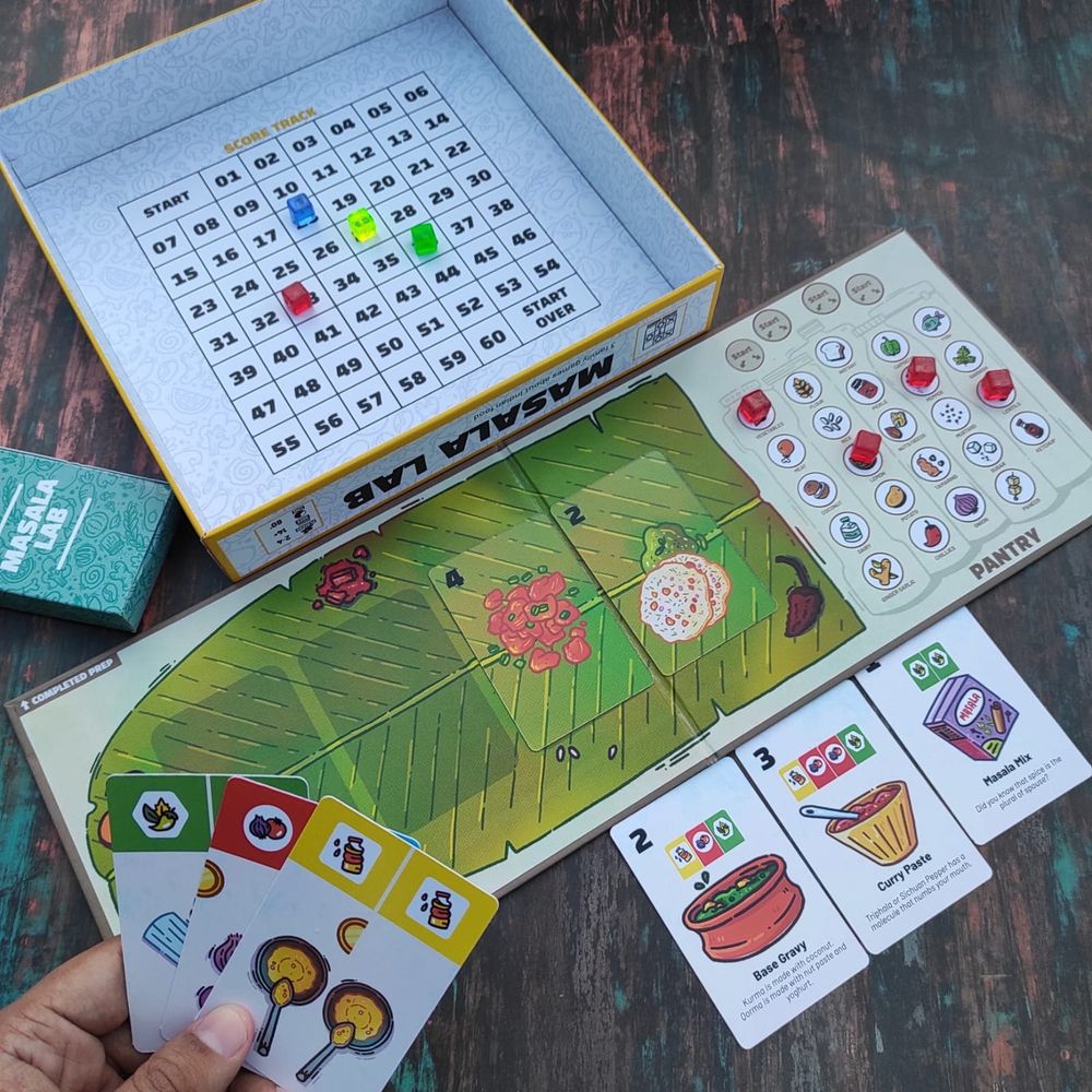 Board game Masala Lab with a banana leaf board, along with some cards with pictures of Indian food on them. 