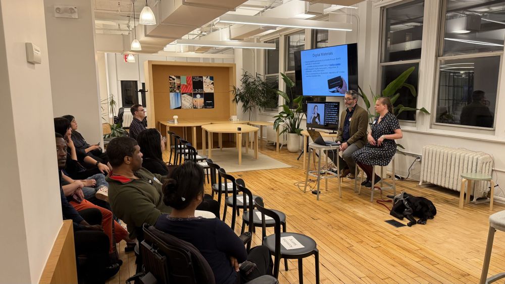 Shane and Chancey seated next to a monitor with a black dog seated next to Chancey.