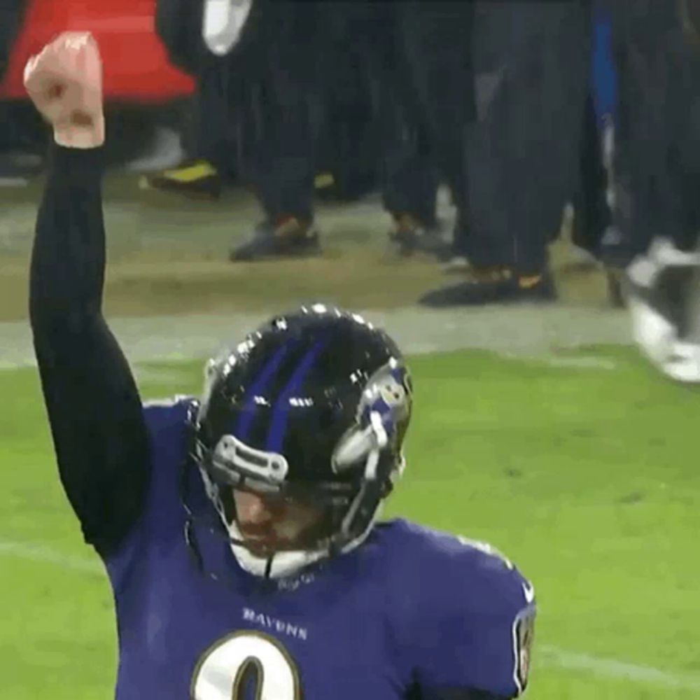 a football player wearing a ravens jersey holds his fist up in the air