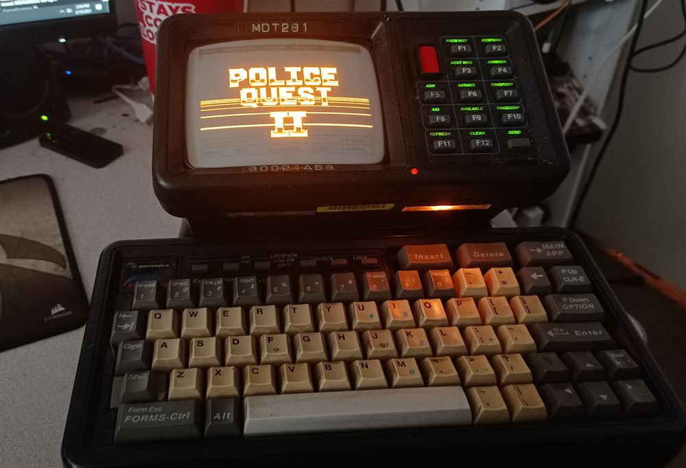 A Motorolla MDT-9100-386. It's a single unit with a clicky keyboard in beige and grey on the front, a small amber CRT on top, next to a grid of grey buttons, along with one red recessed button. It has a lovely glow lighting up the right half of the keyboard (because the bulb on the left was burnt out in this picture) 