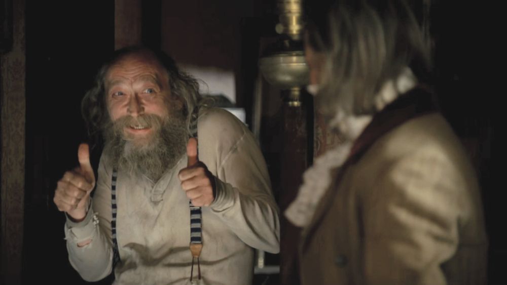 The character Richardson from Deadwood, making a double thumbs-up gesture and grinning.