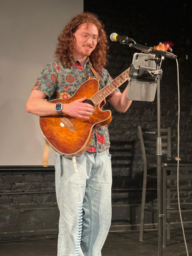 Me, smiling at my iPad while I sing and play an Ibanez Talman acoustic-electric guitar.