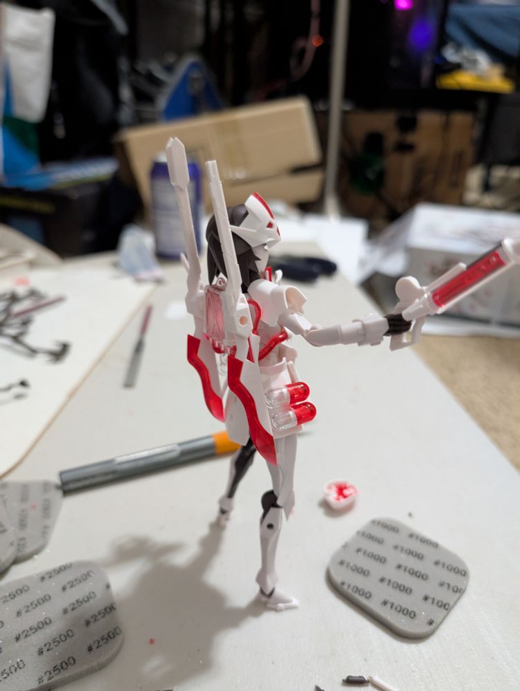 Additional picture of the same model as before but from the back. The model has two scalpel like spears on its back, and is adsorbed with translucent red and white pills to go along with a nurse motif. It is holding a gun in the shape of a large Syringe also made of translucent red and white plastic.