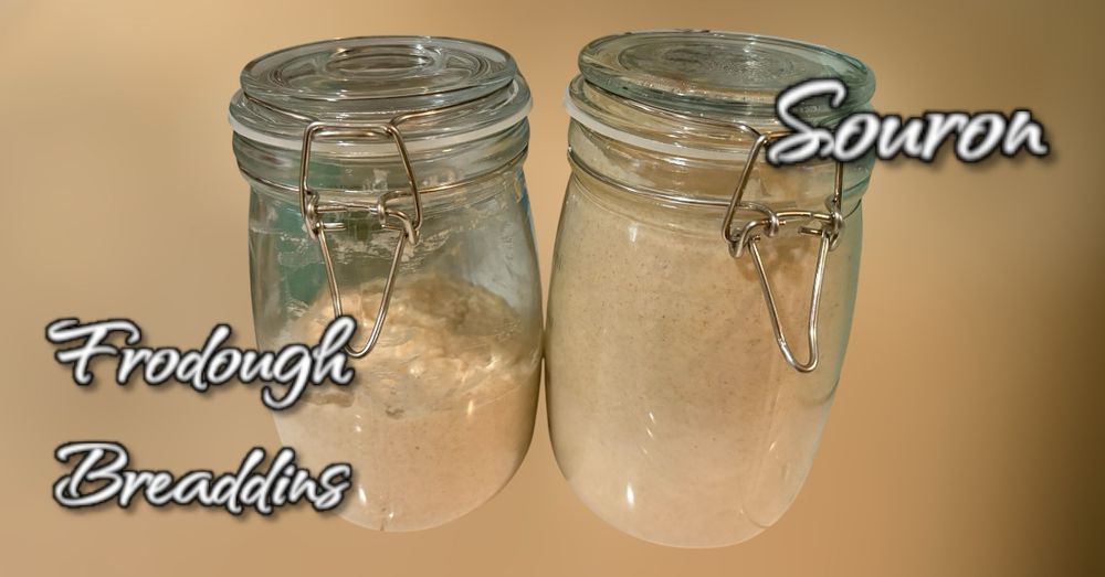 Two glass jars containing sourdough starter sit side by side, with handwritten labels identifying them. The jar on the left contains an active, bubbly sourdough starter named 'Frodough Breaddins,' that was just fed. The jar on the right contains a more settled mixture named  'Souron,' which is the discard portion of the sourdough. Both starters have a creamy beige color characteristic of healthy sourdough culture. The names are clever puns combining bread-making terms with 'Lord of the Rings' character names - Frodo Baggins and Sauron.