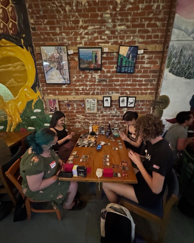 Four people sitting around a table playing a game of Magic: The Gathering Commander.