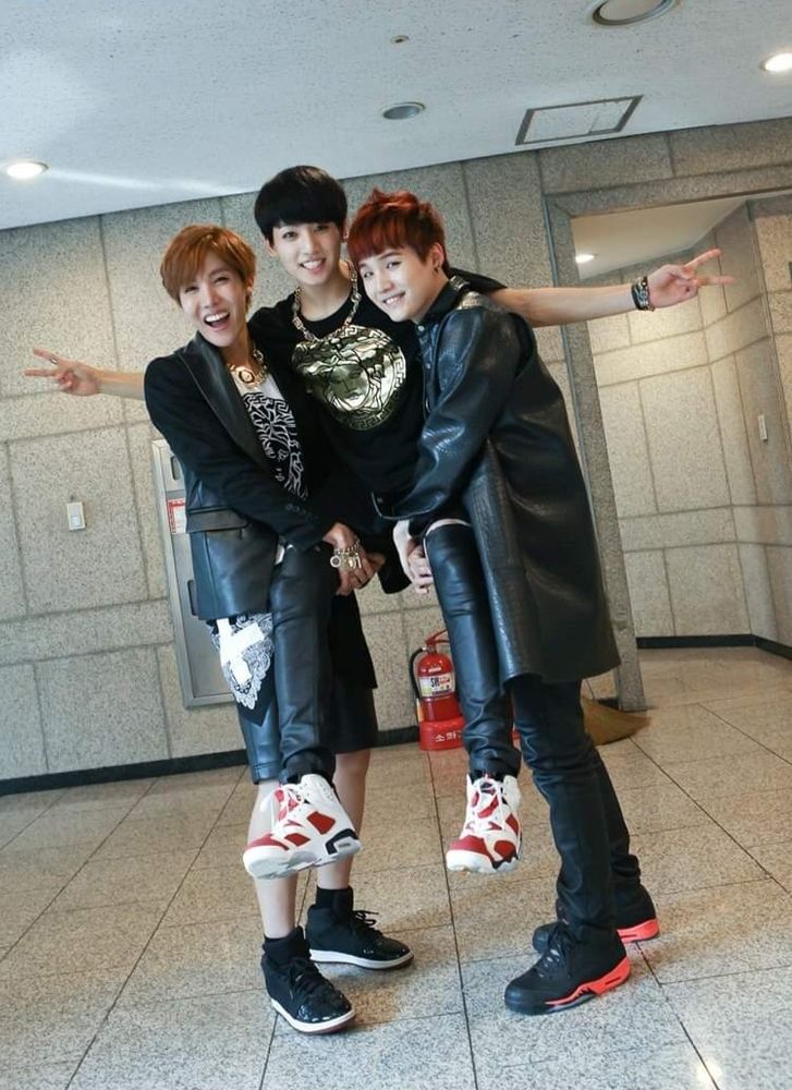 A very young Jhope and Suga making a throne for an even younger Jungkook with their arms. They are all wearing black leather and Versace. 