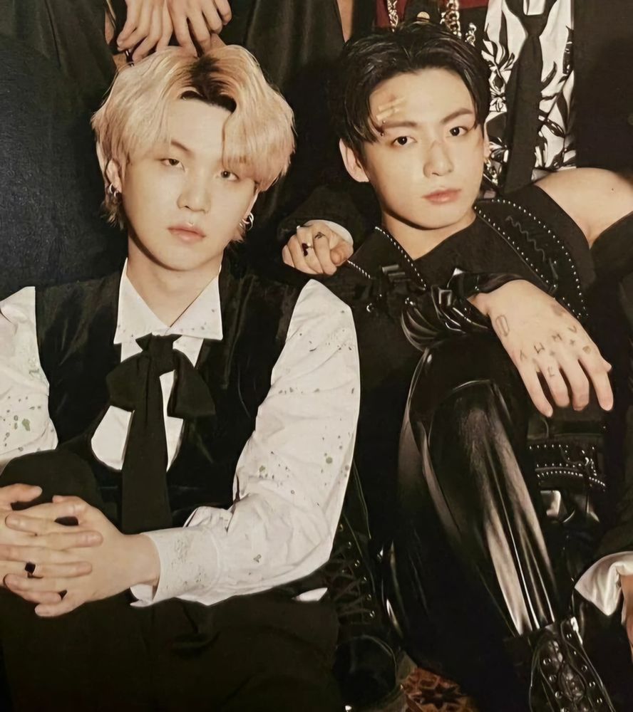 Yoonkook in a villains photoshoot wearing mostly black and looking serious.