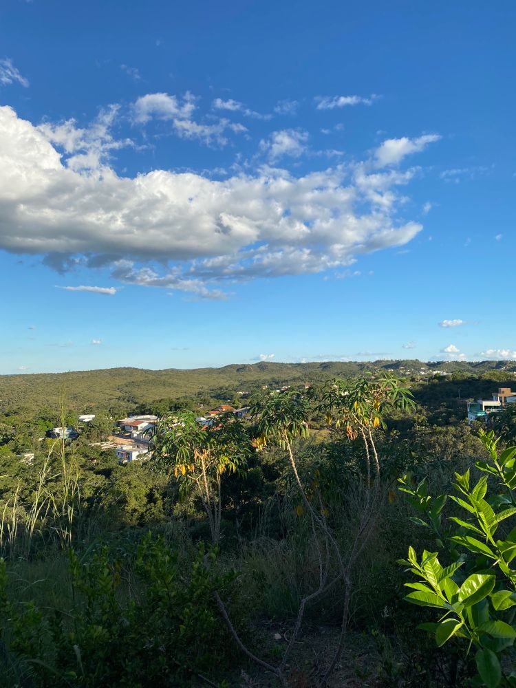 Céu azul no horizonte, contrastando com um morro verde.