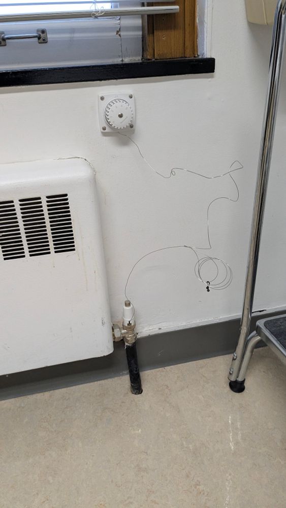 An old radiator with some janky wiring beneath a cracked frame on an old window in the neurology building of Cleveland clinic 