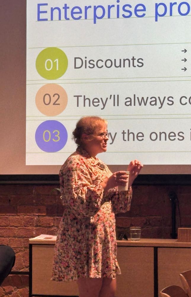 Woman giving a presentation in front of slides and holding a cup of tea that she totally didn’t spill on herself seconds before going on