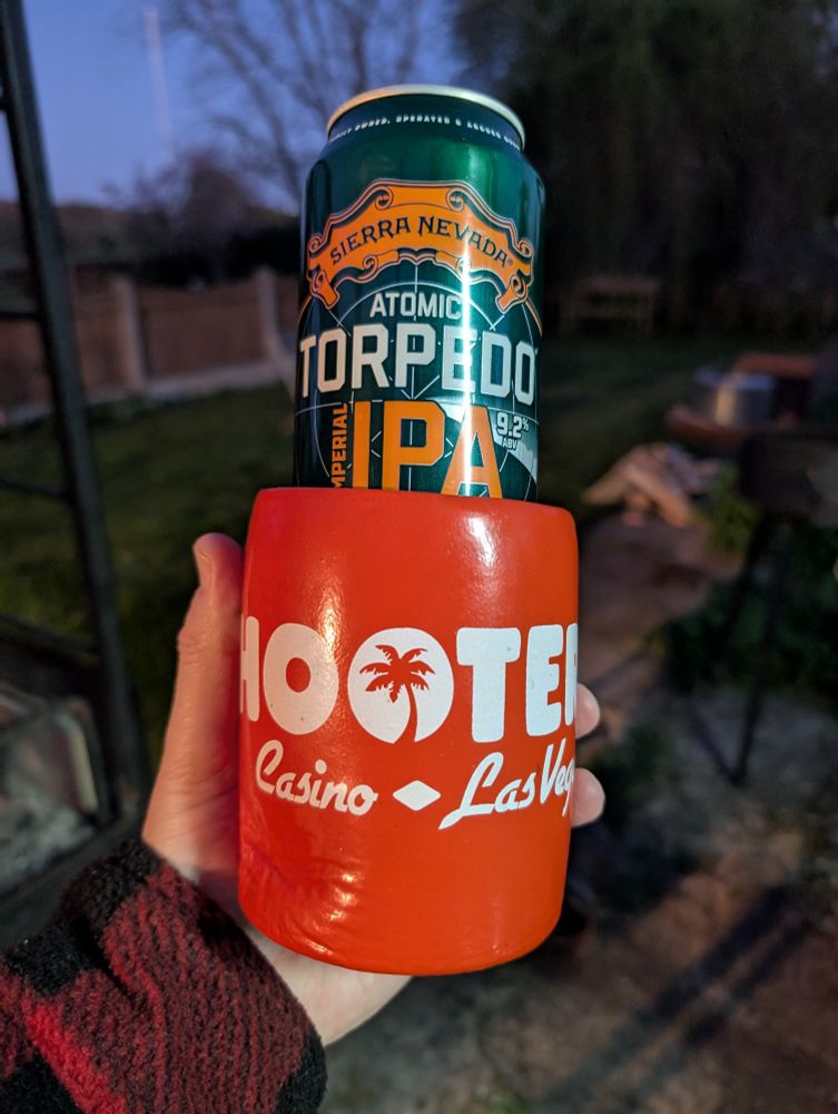A pint can of Sierra Nevada Atomic IPA in a Hooters Koozie which barely reaches half way up the can.