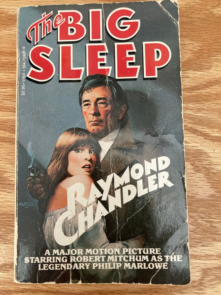 Book cover of The Big Sleep by Raymond Chandler. All caps text at bottom reads “A major motion picture starring Robert Mitchum as the legendary Philip Marlowe”