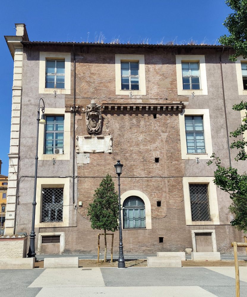A concrete building with a segment of the façade looking totally different, consisting of red tiles and marble entablatures