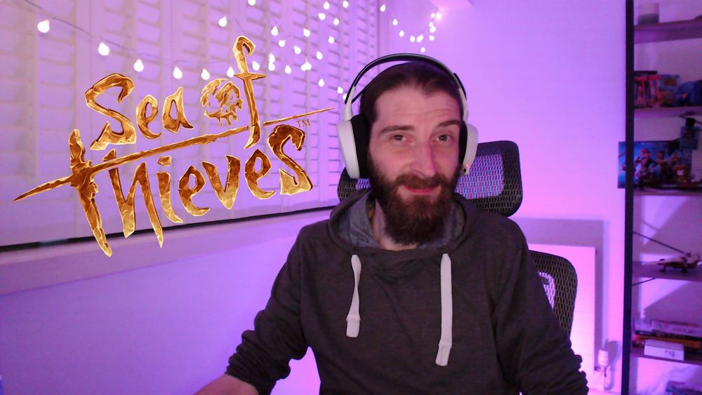 Goofy streamer in a purple lit room with the Sea of Thieves logo.