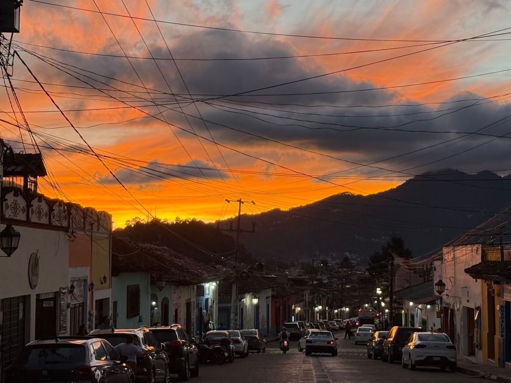 Bright orange and yellow sunset over mountains, looking down a street in Mexico