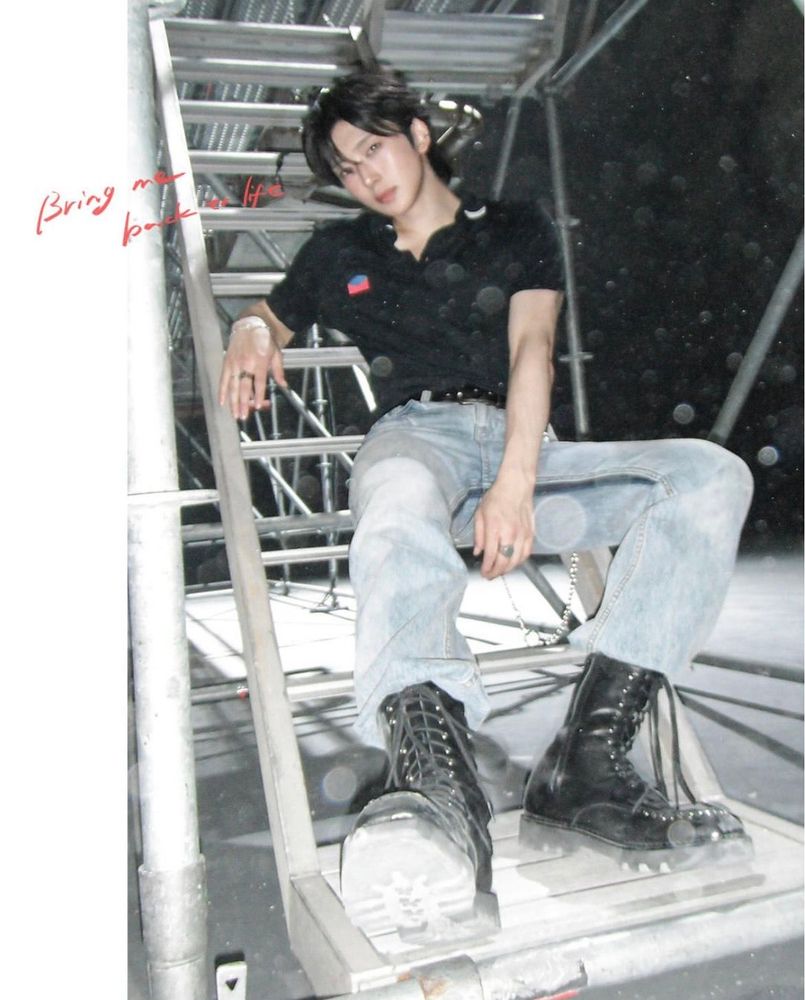 fuma sitting on metal stairs wearing black polo, light wash jeans and black boots. i am so enamored w this photo