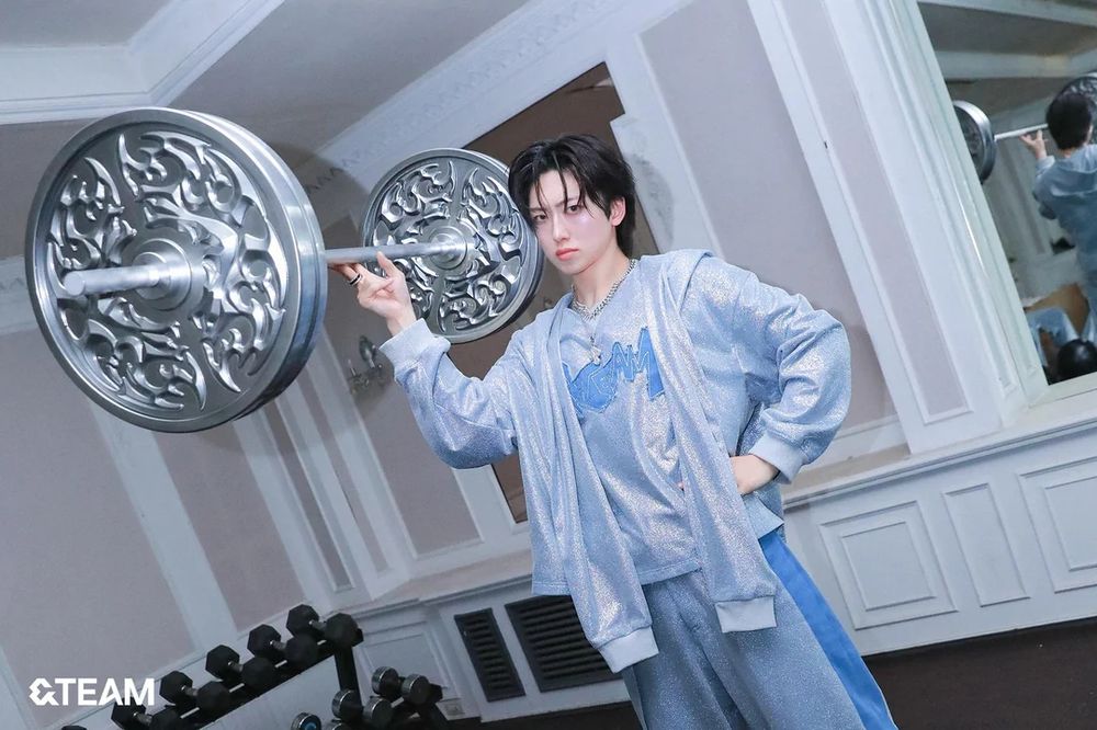 fuma in light blue sparkly tracksuit from lunatic mv holding a prop weight (that's super big and would prob be like idk 100 lb or something) with just three fingers