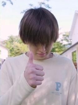 fuma shortly after waking up w his bangs covering his face while his head is tilted down. he is giving a thumbs up