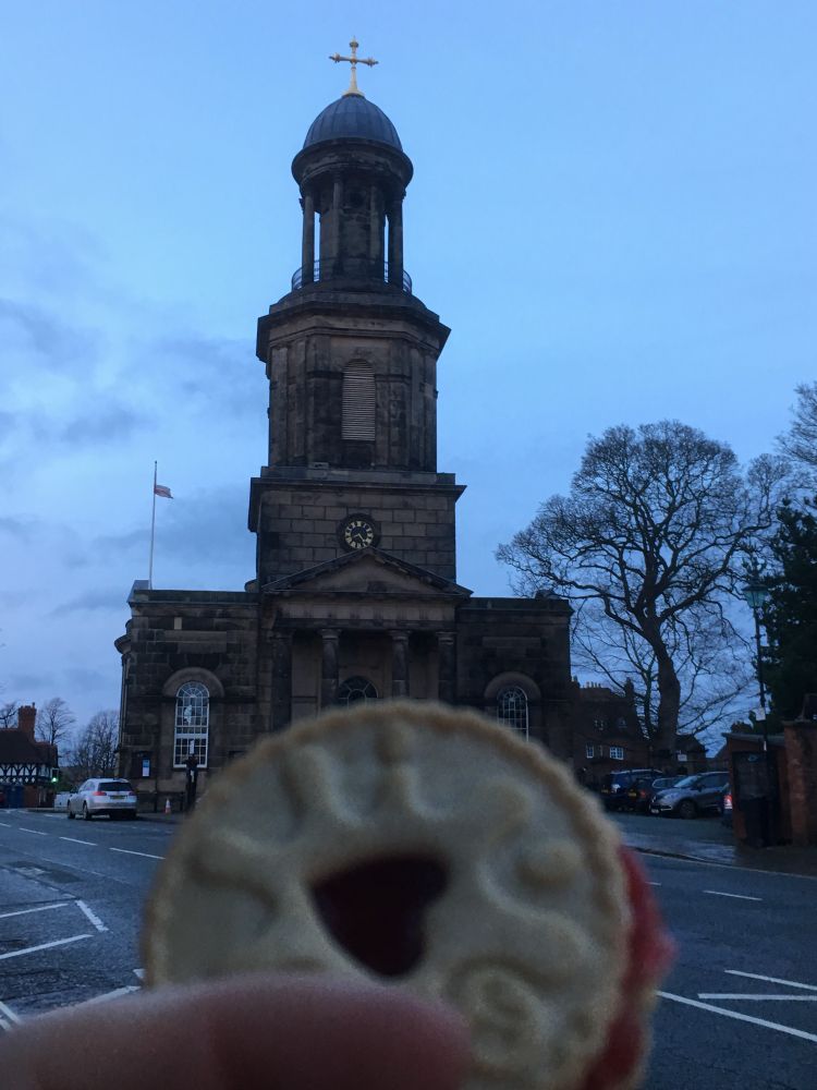 A Shrewsbury biscuit with heart-shaped jam is held in front of Shrewsbury’s town hall.