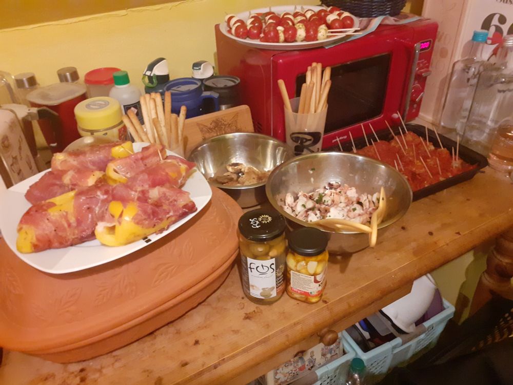 Foto mit Essen für Silvester: Paprika mit Machego gefällt und Serrano Schinken ummantelt; panierte Champignons, Tintenfischsalat, Albóndigas in Tomatensauce; Tomate-Mozzi-Spieße, Grissini mit Rosmarin, Grissini klassisch, Oliven mit Mandeln gefüllt, in Chiliöl eingelegte Knoblauchzehen