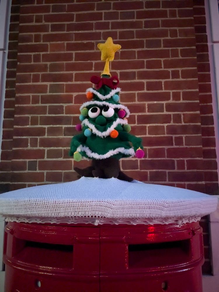 Christmas themed crochet top on the postbox, Christmas tree with googly eyes, decorated and a yellow star and red bow in top, white cover snow like 