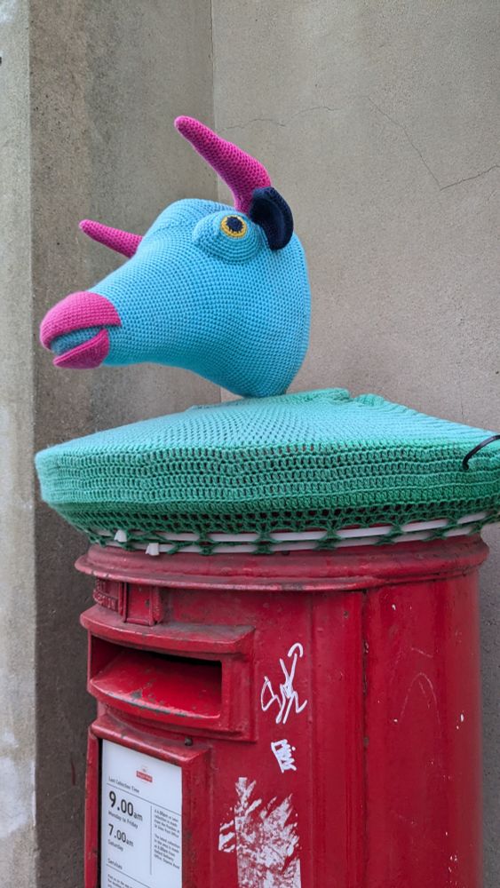 Crochet top, light green blue bottom covering the circular part and a blue monster head with pink horns