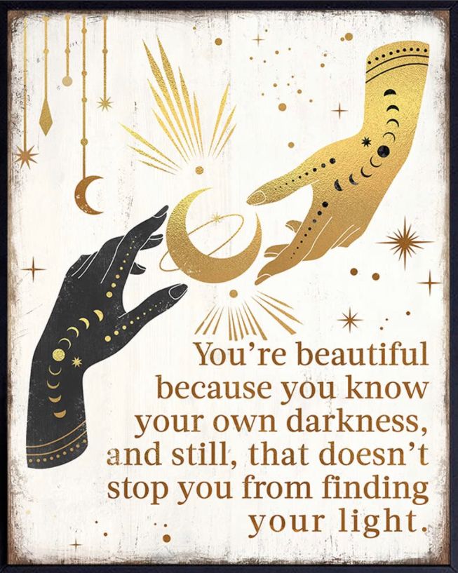 Two hands tattooed with the phases of the moon, one black and one gold, encircle celestial symbols. They are captioned: “You’re beautiful because you know your own darkness, and still, that doesn’t stop you from finding your light.”