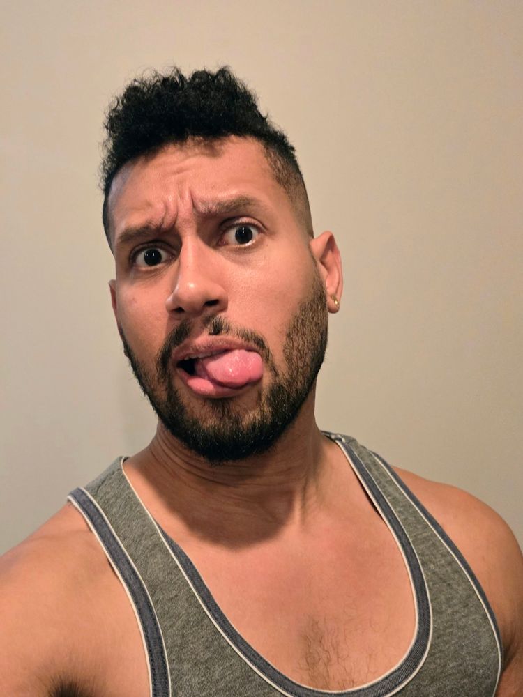 A selfie of some scruffy half black guy with low self esteem (it's me) sticking his tongue out at the camera to avoid smiling 