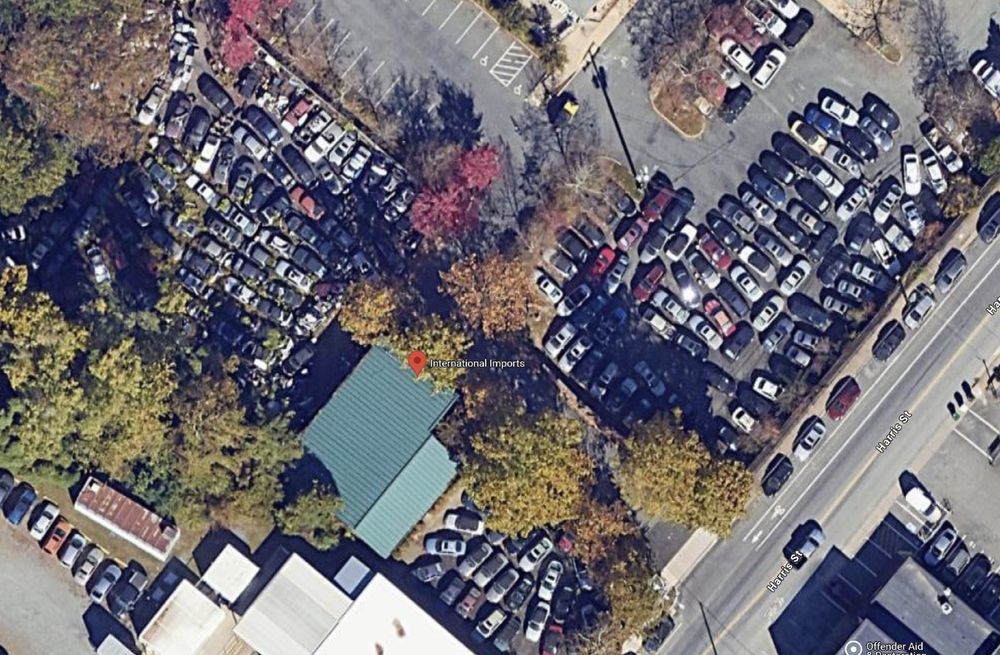 An aerial photograph of International Imports in Charlottesville, Virginia that shows a large number of SAAB cars parked close together like a junkyard. The business is one of the few places to get a SAAB repaired on the eastern seaboard of the United States, but has a local reputation as a nuisance for its accumulation of inoperable vehicles.