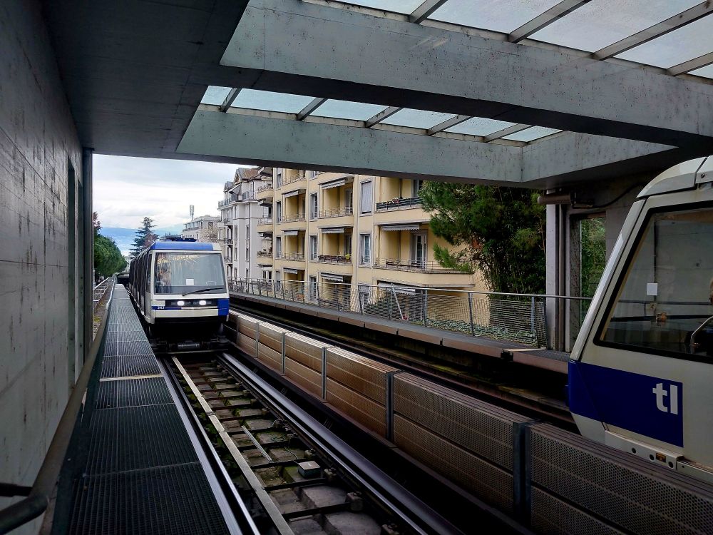 2 Metrozüge in Lausanne. Einer ist von vorne zu sehen und erreicht gleich eine Station. Von dem anderen ist die Spitze zu sehen und er wird gleich den Bahnhof verlassen. 