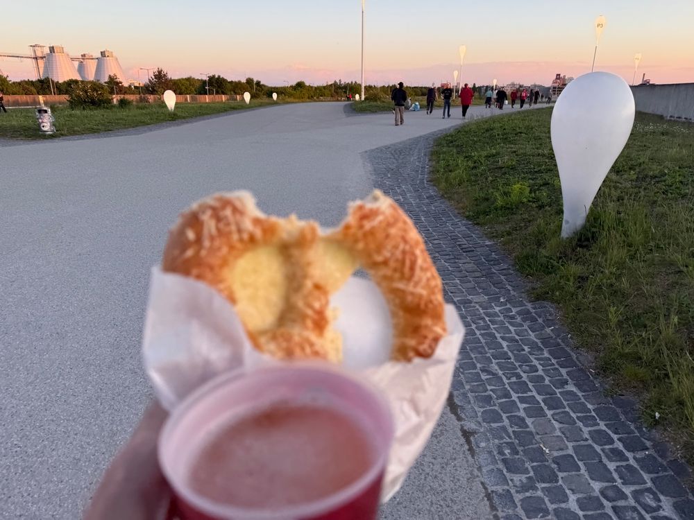 Out of focus, partially eaten cheese pretzel and a beer