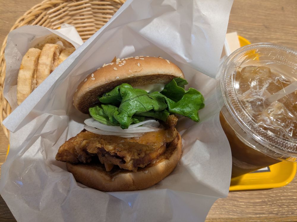 カゴにレモンチキンバーガー。レモンチキンと玉ねぎレタス、バンズ。アイスコーヒー。レンコンフライ。