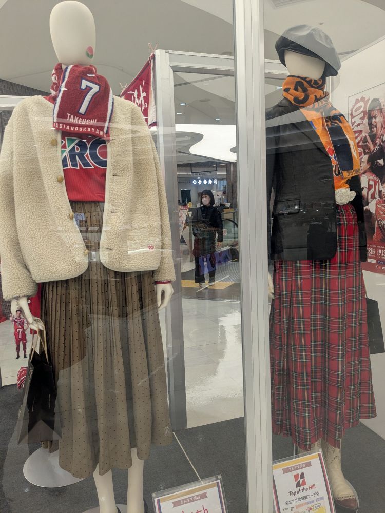 ファジアーノ岡山ユニ黒い上着、（白い上着、7番タオマフ、グレーのプリーツスカート）ユニと清水エスパルスユニ（黒い上着、タオマフ、赤タータンチェックのスカート）コーデのマネキン。
