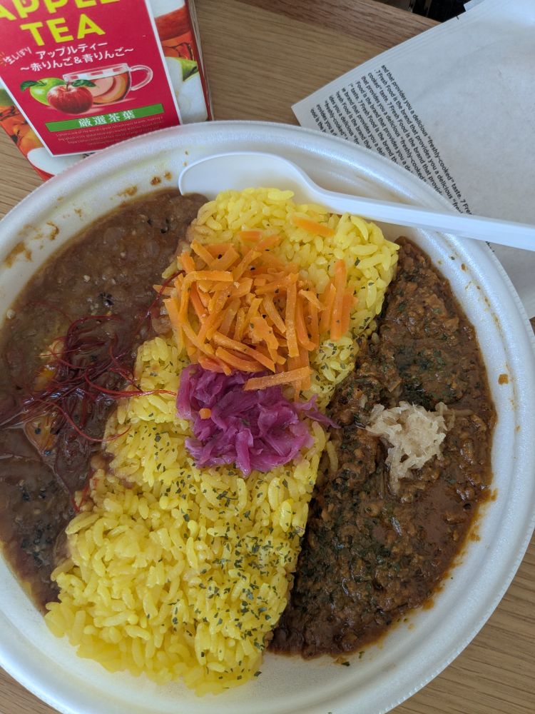 あいがけスパイスカレー。真ん中に黄色いサフランライス、トッピングににんじんと紫キャベツかな？リプトンアップルティー。ハッシュポテト。