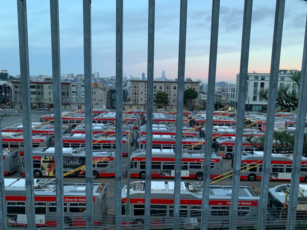 A lot of busses in San Francisco behind a gate