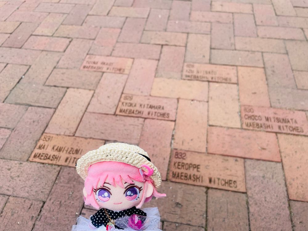 写真。手前にユイナぬい。前橋文学館前の歩道のレンガ。前橋ウィッチーズのキャラクターとケロッペの名前がレンガに刻まれている。