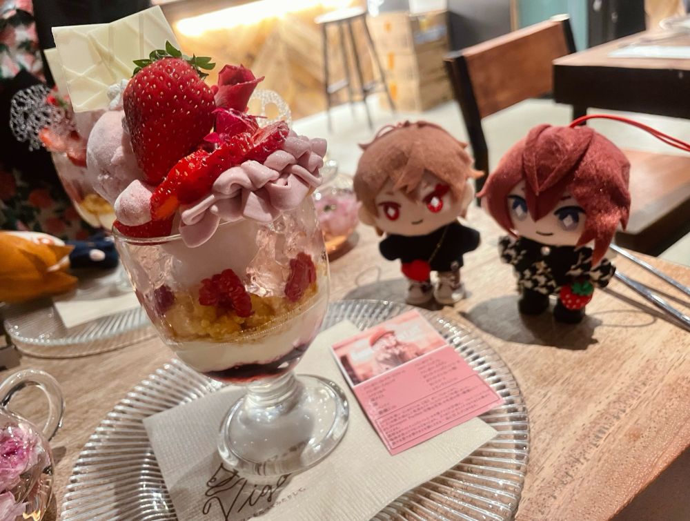 豪華ないちごパフェとリドルとエースのぬいぐるみの写真。