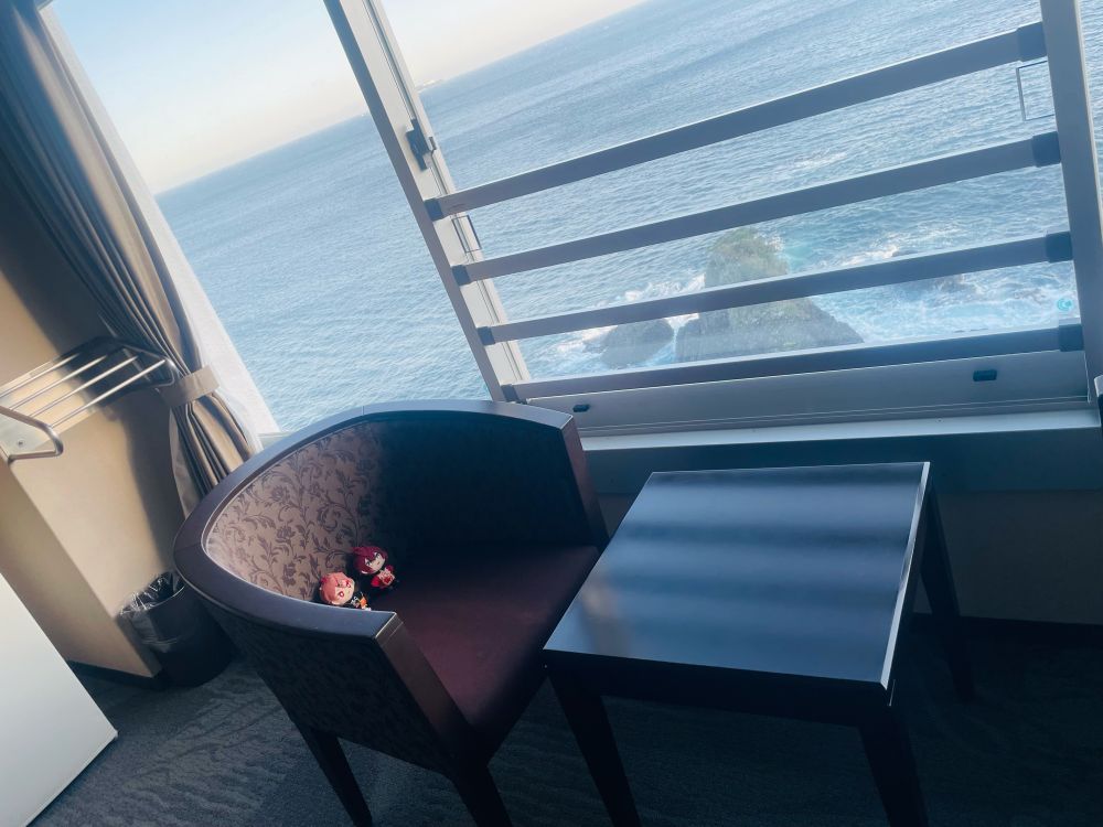 写真。ホテルニューアカオの客室の広縁、椅子の上にエスぬいとリドぬい。窓の外には海。