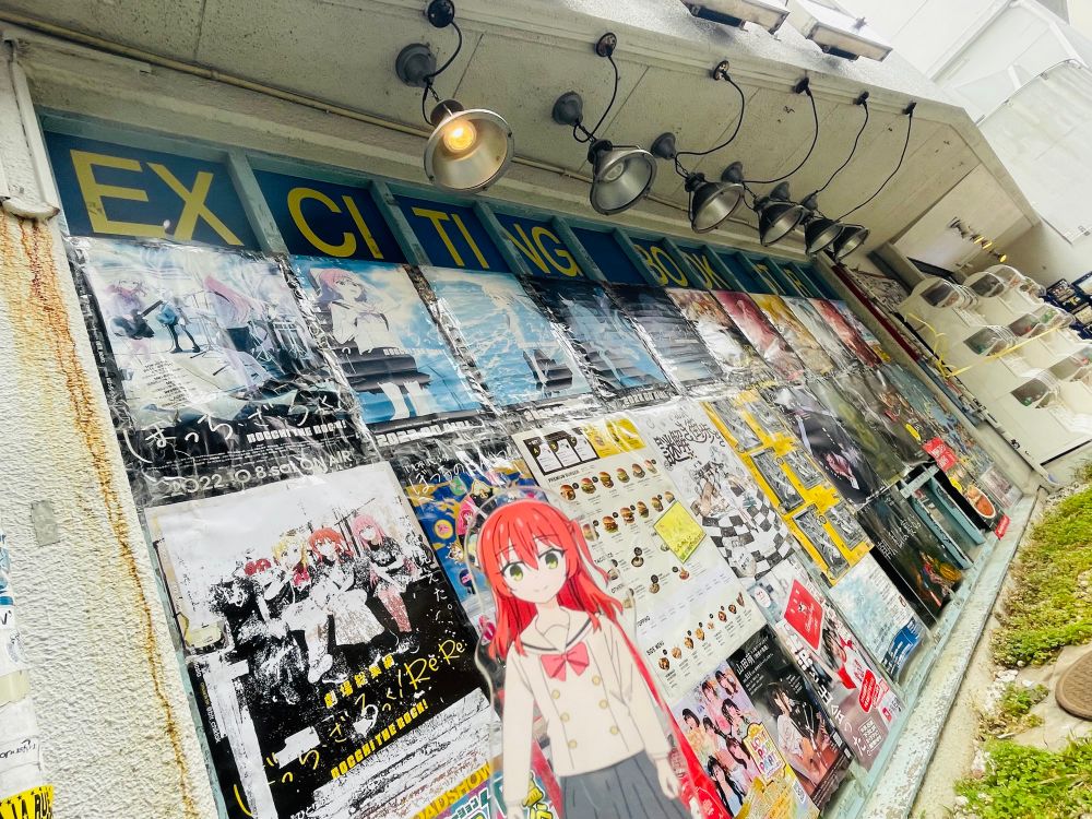 写真。下北沢のヴィレヴァン前、色褪せたぼざろポスターたちと喜多郁代アクリルスタンド。