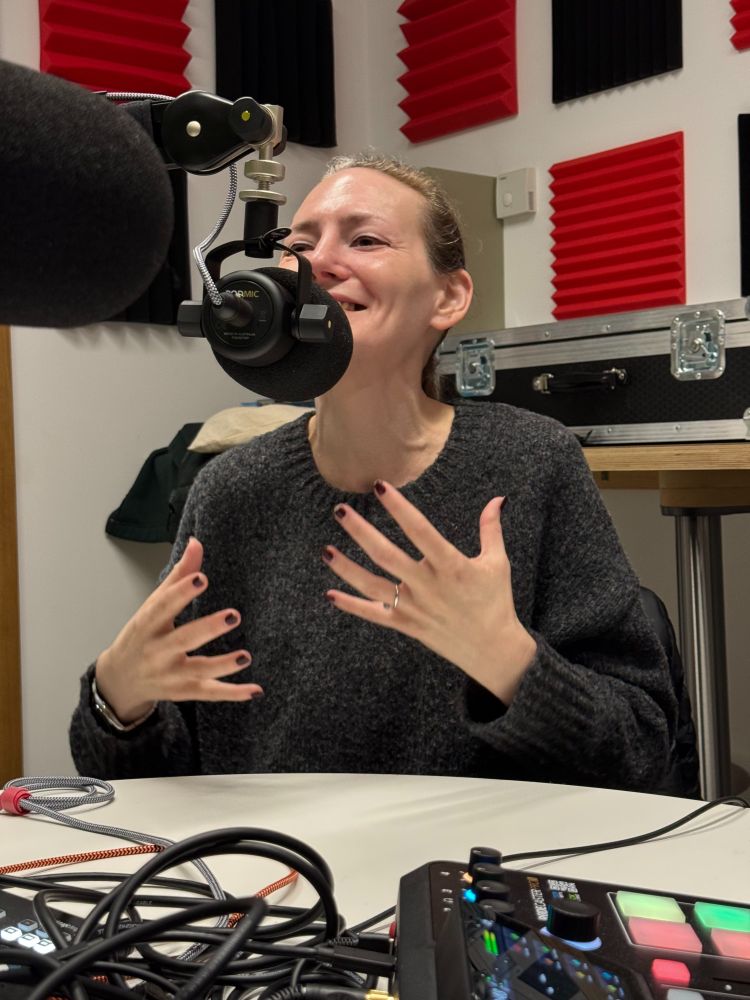 Alexandra Harrington gestures while talking into a microphone in the podcast studio