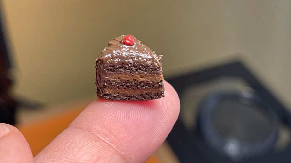 Image of small chocolate cake slice on a finger tip
