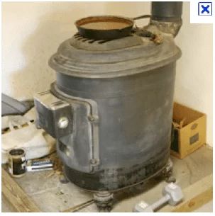 Ashley Wood Stove with thermostatic control - door openings in the front and on top, resting on four feet.  Chimney up at the top rear.