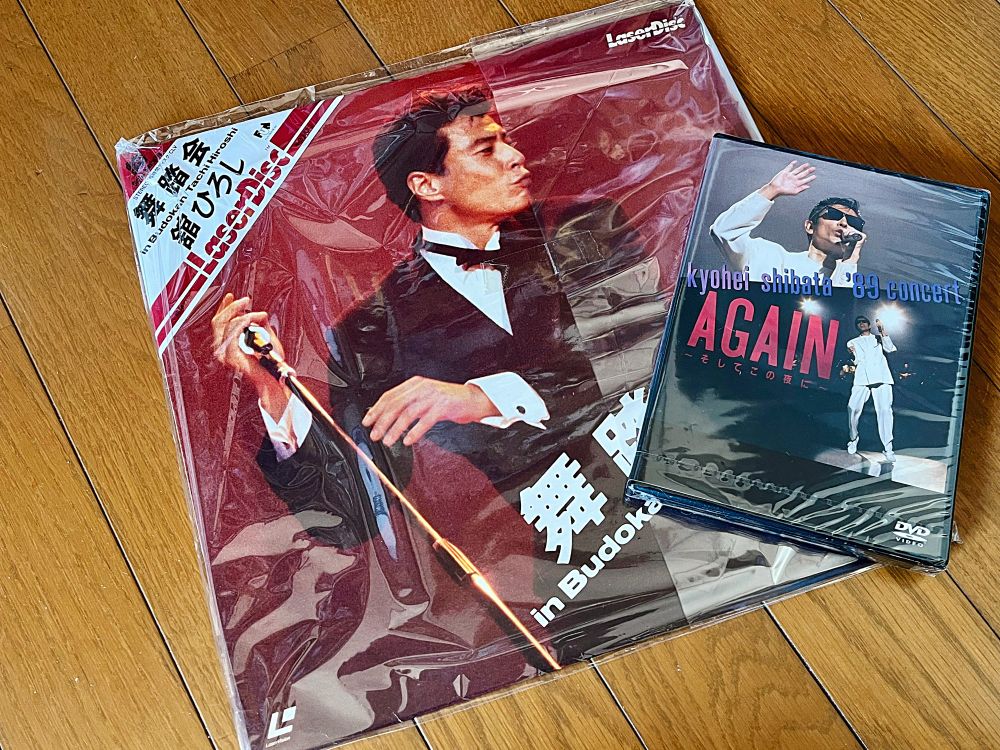 舘ひろしの『舞踏会』のレーザーディスクと柴田恭兵の『AGAIN-そしてこの夜に-』のDVDが並んで置かれている。