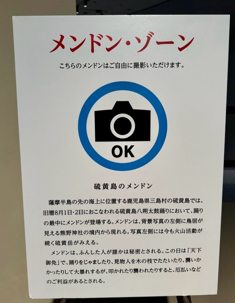 メンドン・ゾーン
こちらのメンドンはご自由に撮影いただけます。の下に解説文がある。

硫黄島のメンドン
薩摩半島の先の海上に位置する鹿児島県三島村の硫黄島では、旧暦8月1日・2日におこなわれる硫黄島八朔太鼓踊りにおいて、踊りの最中にメンドンが登場する。メンドンは、背景写真の左側に鳥居が見える熊野神社の境内から現れる。写真左側には今も火山活動が続く硫黄岳がみえる。
メンドンは、ふんした人が誰かは秘密とされる。この日は「天下御免」で、踊りをじゃましたり、見物人を木の枝でたたいたり、襲いかかったりして大暴れするが、叩かれたり襲われたりすると、厄払いなど のご利益があるとされる。