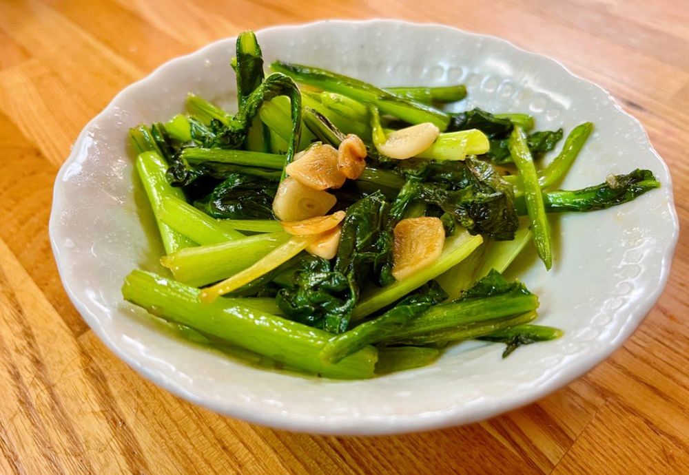 青梗菜をひと口大に切り、にんにくを入れて炒めなものが皿の上に乗せられている。