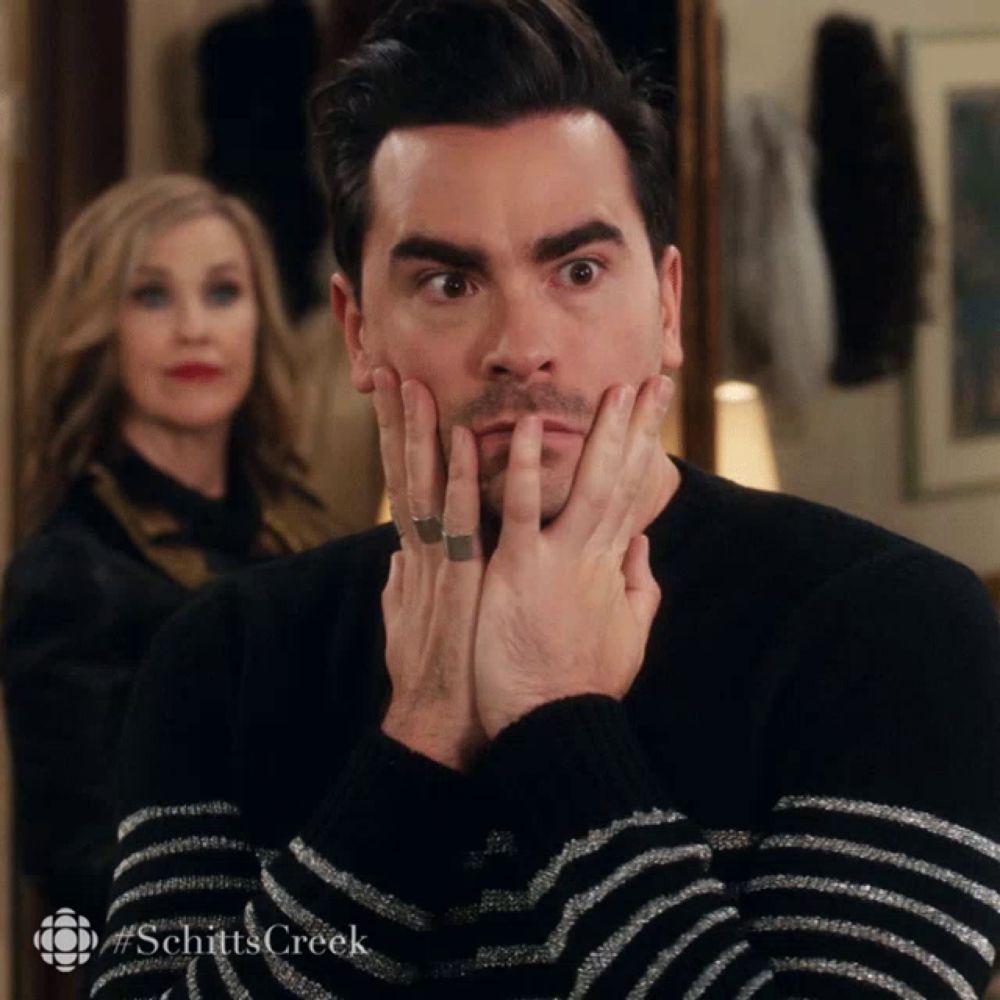 a man wearing a black and white striped sweater with the word schitt 's creek at the bottom