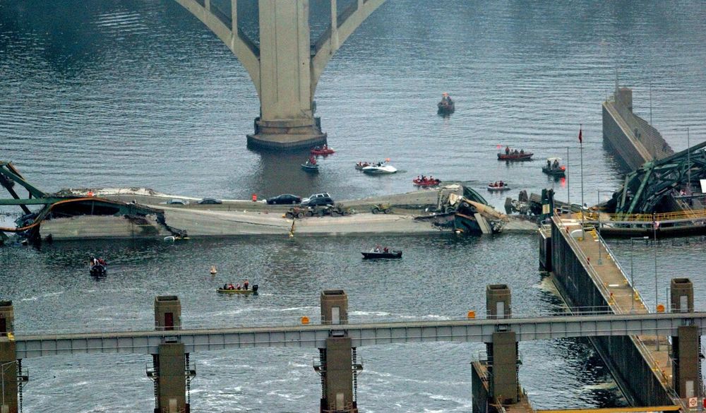 Rescue workers use boats to search for people near a collapsed bridge lying in a river. 