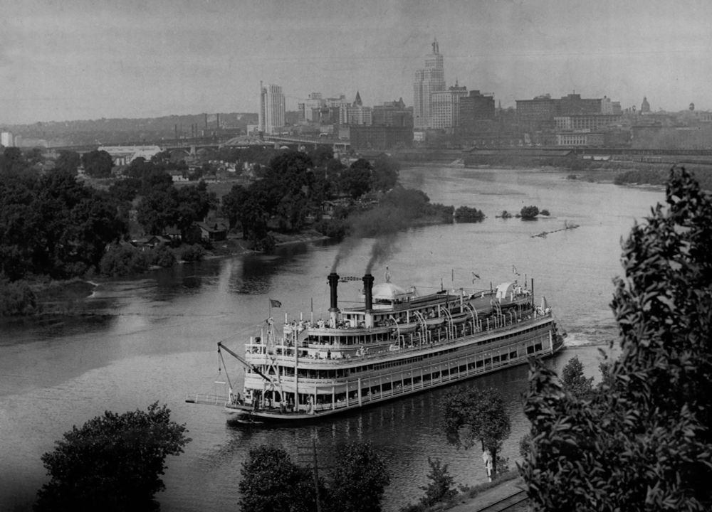 A paddleboat steams down a river with the St. Paul skyline in the background. 